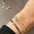 Goudkleurige dunne bangle armband met groene steentjes