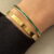 Goudkleurige dunne bangle armband met groene steentjes